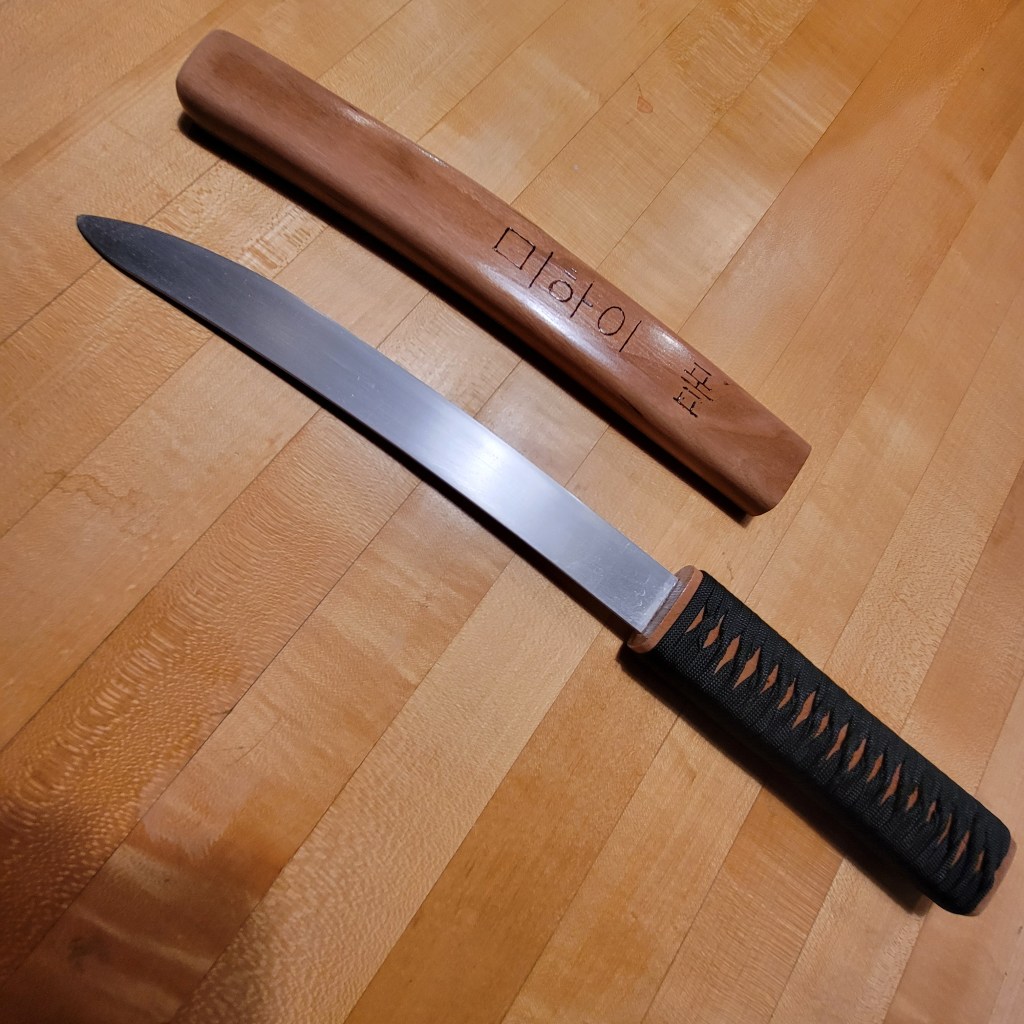 Tanto-like knife next to its wooden scabbard.