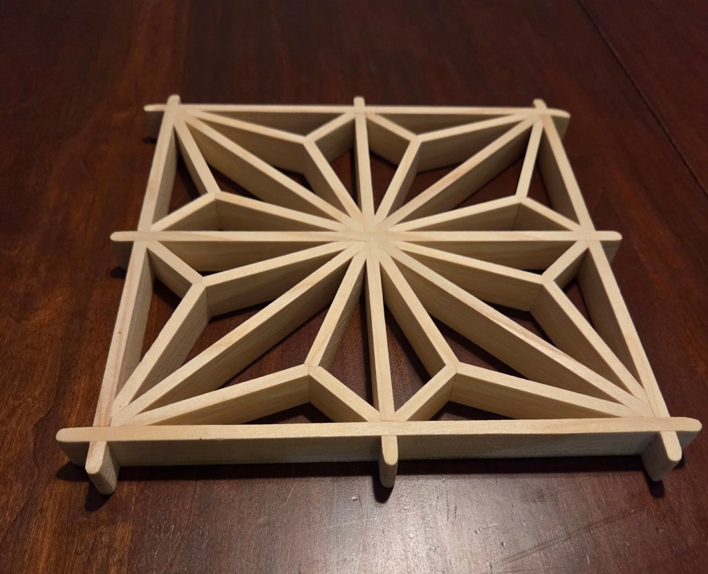 Wooden trivet with a geometric pattern resembling a leaf.